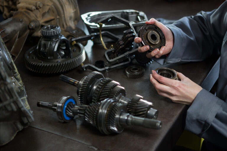 Close-up of female mechanic holding spare parts of car at repair garage